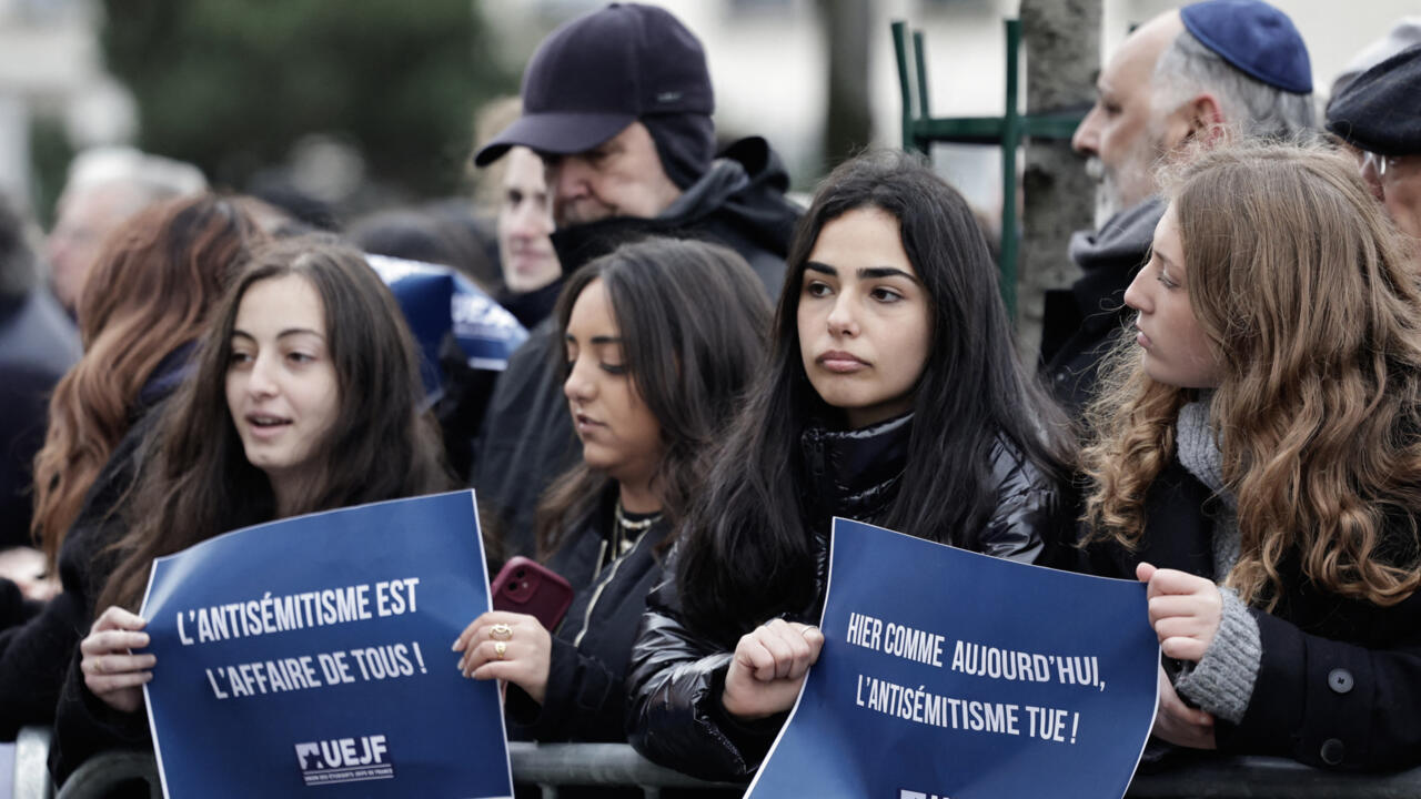 Attendees stand vigil outside the Hypercacher Supermarket in Paris on January 9, 2025, during a commemoration marking the 10th anniversary of an Islamist attack.