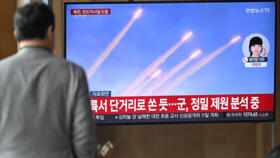 A man watches a television screen showing a news broadcast with file footage of a North Korean missile test at a train station in Seoul on March 10, 2025. 