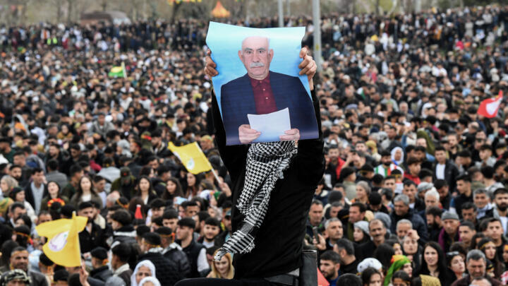 A man holds a poster of Abdullah Ocalan, Turkish-jailed founder of the Kurdistan Workers' Party (PKK), during a gathering of Turkish Kurds for Nowruz celebrations marking the New Year of the Persian c