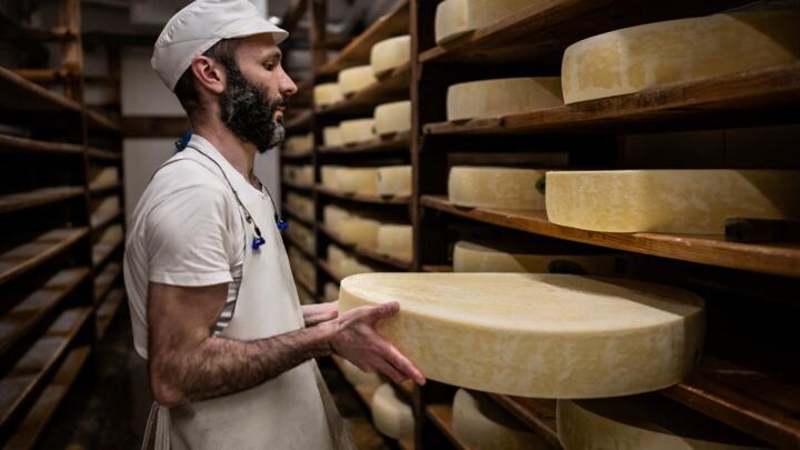 An employee works in the maturing cellar at a Comte cheese dairy in Arc-sous-Cicon, eastern France on March 20, 2024. 