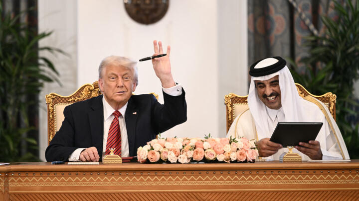 L'émir du Qatar, Cheikh Tamim bin Hamad al-Thani (R), réagit alors que le président américain Donald Trump lève son stylo lors d'une cérémonie de signature au palais royal de Doha, le 14 mai 2025.