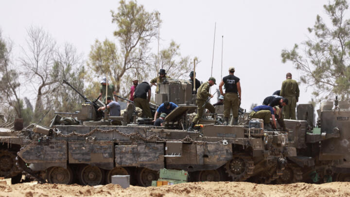 Tropas israelíes trabajan en sus vehículos blindados en una posición junto a la frontera de Israel con la Franja de Gaza el 18 de mayo de 2025.