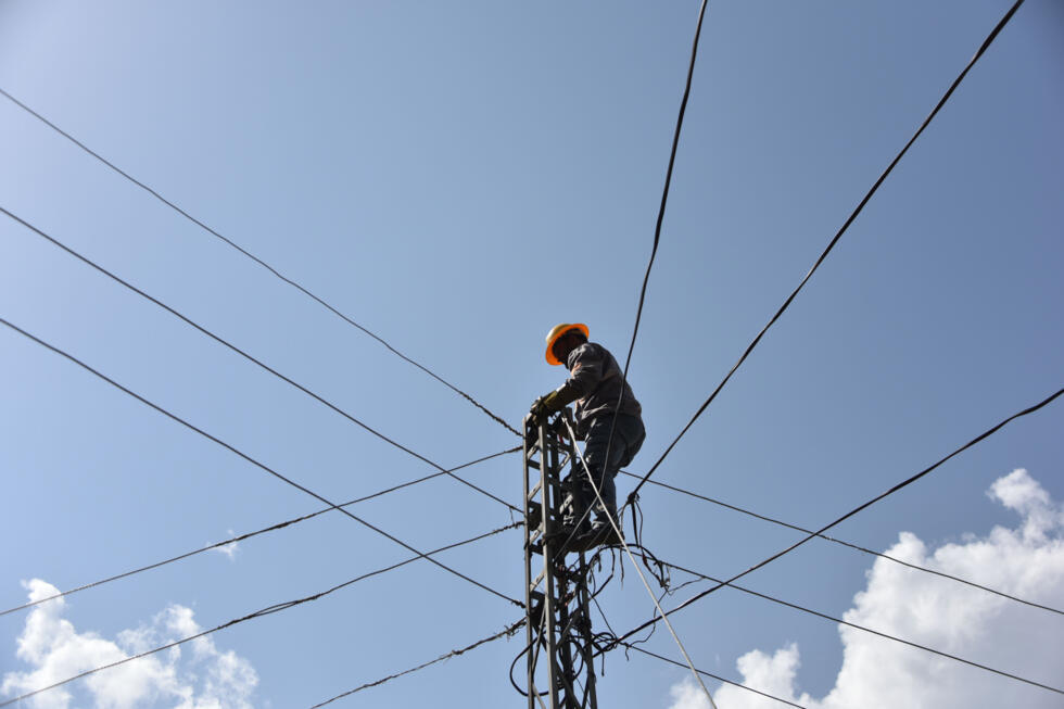 A tecnician repairs a damaged power line following cross-border shelling in Jura village