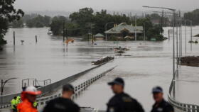 Police officers and road workers are seen in front of a submerged structure visible in floodwaters in the suburb of Windsor as the state of New South Wales experiences widespread flooding and severe weather, in Sydney, Australia, March 22, 2021.